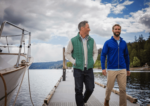 Man on a dock walking with a friend wearing Cutter & Buck Rainier PrimaLoft® Mens Eco Insulated Full Zip Puffer Vest