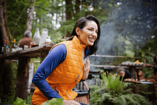 Woman at a bonfire wearing Cutter & Buck Rainier PrimaLoft® Womens Eco Insulated Full Zip Puffer Vest