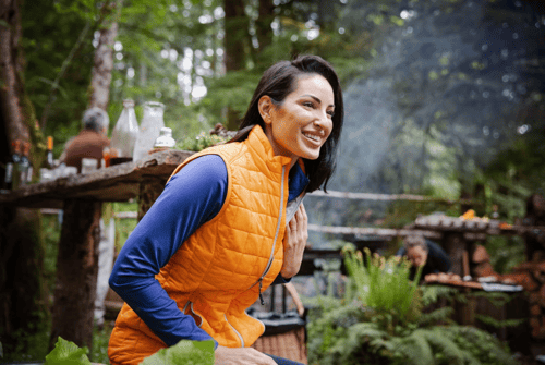 woman at campfire wearing orange puffer vest