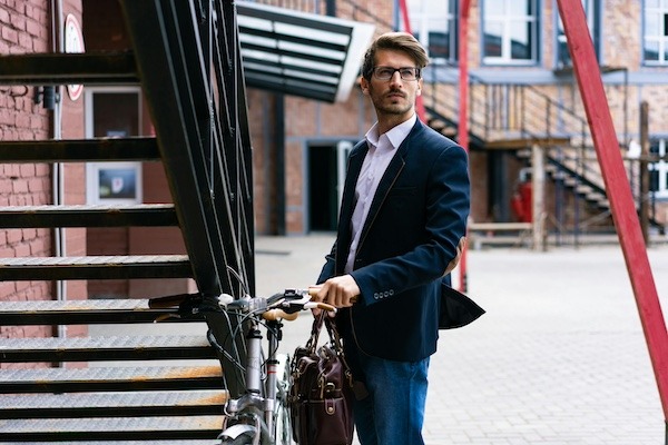 Millennial businessman parking his bike before walking into work