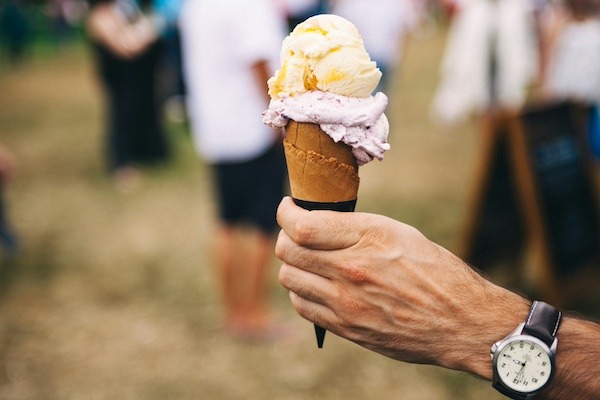 A man holding a double scooped ice cream cone at a food festival