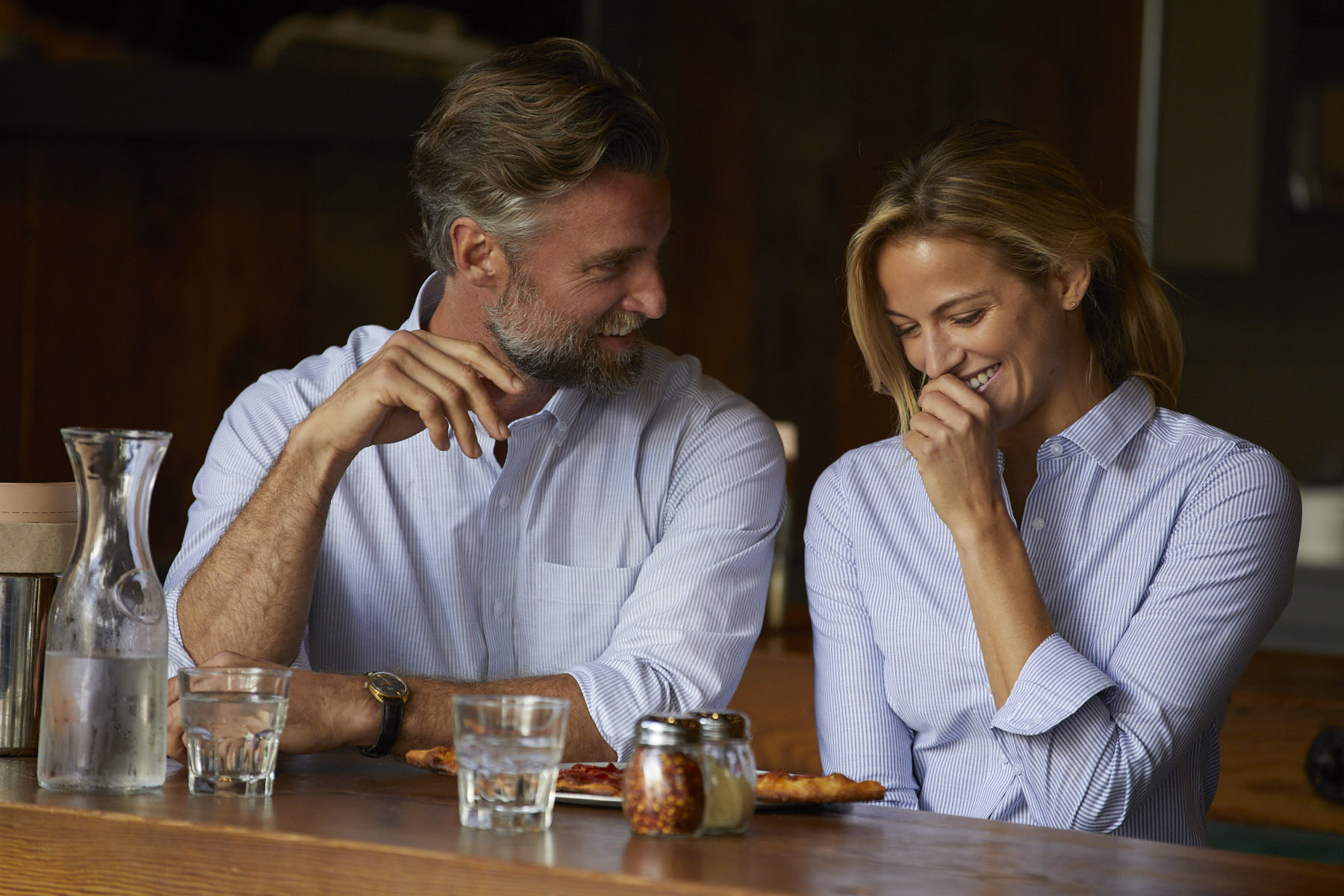 Man and woman laughing, while wearing blue striped Cutter and Buck shirts at a brewery