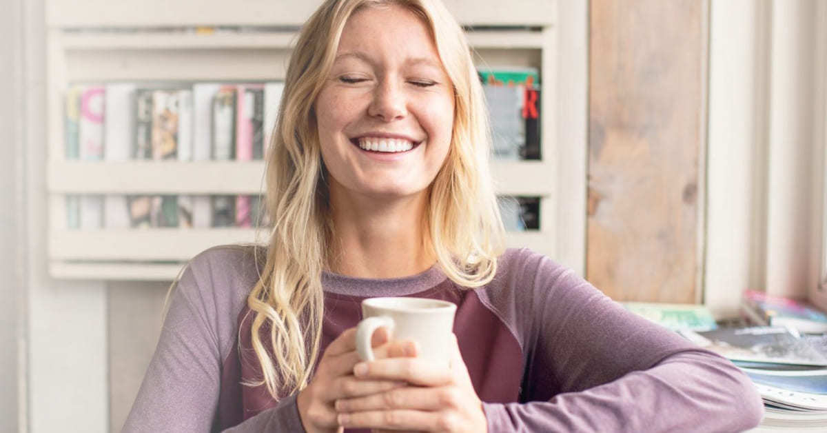 Woman smiling and having coffee while wearing Cutter and Buck